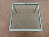an image of a glass table with metal legs on a carpeted floor
