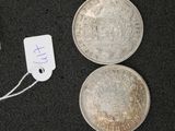 two silver coins and a silver coin with a price tag on a black surface