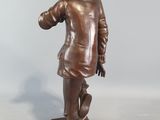 bronze statue of a man in a hat and coat with a cane