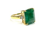 a close up of a ring with a green stone and diamonds