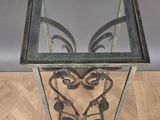 an antique wrought iron and glass side table with a glass top