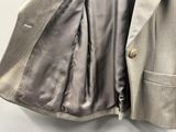 une veste de costume suspendue à un cintre accroché au mur