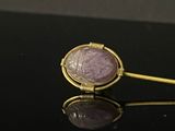 purple stone in a gold - plated ring on a black surface