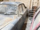 two old cars that are parked in a garage