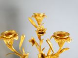 a gold candle holder with flowers in it on a table