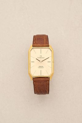 a close up of a watch on a white surface with a brown strap