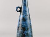 un vase bleu avec une anse noire sur fond blanc