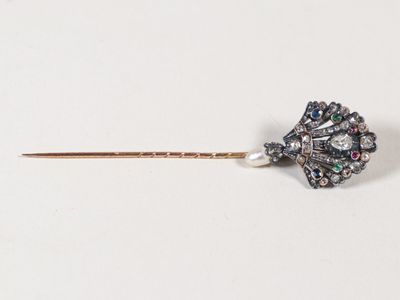 une image représentant une broche en forme de fleur, composée d'un diamant et d'une perle, fixée sur une tige