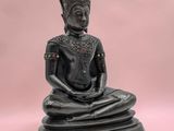 une statue de Bouddha noire posée sur un socle en bois