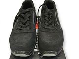 une paire de baskets noires posée sur une boîte, sur une surface blanche