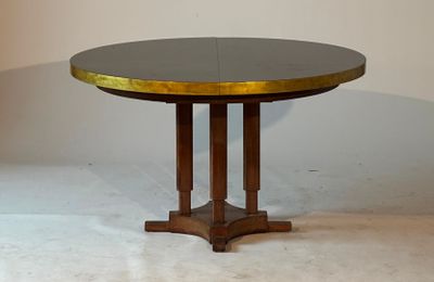 une petite table ronde au plateau doré, posée sur un sol blanc