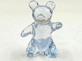 une figurine d'ours en verre posée sur une surface blanche