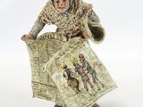 figurine of a woman reading a newspaper on a white background