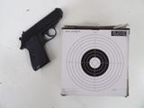 un pistolet et une cible posés sur une table blanche