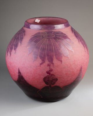 un vase rose orné de fleurs violettes, posé sur un fond blanc