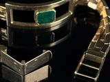 a close up of a bracelet with a green stone on it