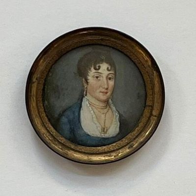 tableau représentant une femme en robe bleue, dans un cadre doré, accroché à un mur blanc