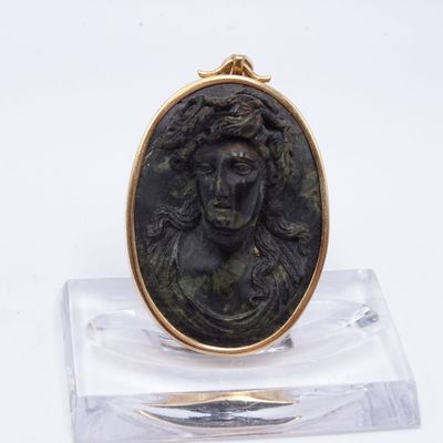 un gros plan d'un petit médaillon en bronze posé sur un socle transparent