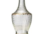 a clear glass bottle with a gold rim on a white surface