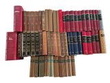 many books are stacked on top of each other on a white surface