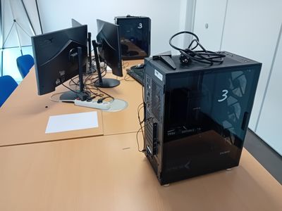 trois écrans d'ordinateur posés sur une table dans une pièce