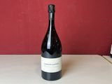 trois bouteilles de vin sont posées sur une table devant un mur rouge
