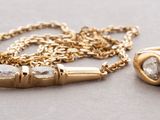 two gold rings and a gold chain on a gray surface