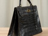 a black crocodile skin handbag sitting on top of a wooden table
