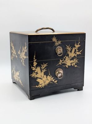 une image représentant une commode noire et dorée sur fond blanc
