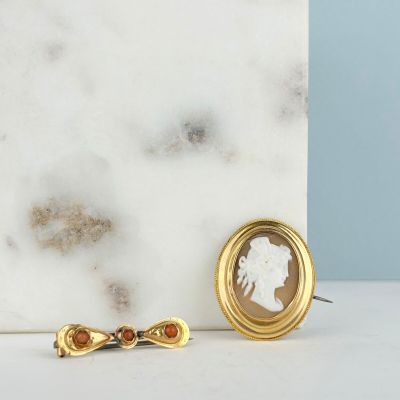two pieces of jewelry sitting on top of a marble counter top