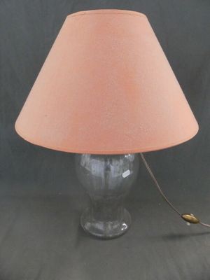 une lampe en verre surmontée d'un abat-jour rose