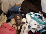 a pile of clothes and a book on a bed