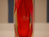 a red glass vase with a red handle on a table