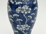 un vase bleu orné de fleurs blanches sur fond blanc