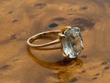 yellow gold ring with a blue topaz stone on top of a wooden table