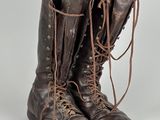 une paire de bottes en cuir marron à lacets posées sur une surface blanche