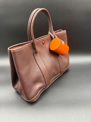 an image of a brown purse with a orange tag on it