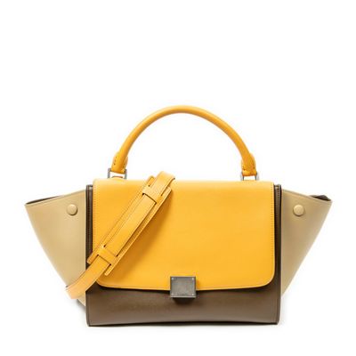 a yellow and brown handbag sitting on top of a white surface