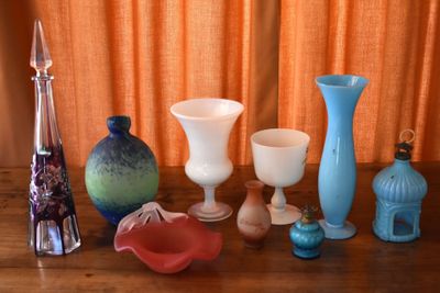 many different vases sitting on a table in front of an orange curtain