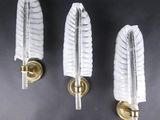 trois appliques murales en verre blanc fixées sur un mur noir