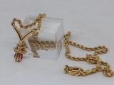 a small box with a gold chain and a red bead on it