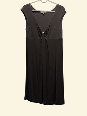 the black dress is hanging on a hanger on a white wall