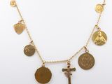 a close up of a gold necklace with a cross and other charms