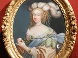 un tableau représentant une femme, dans un cadre doré, accroché à un mur rouge