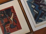 two framed art pieces on a table next to each other