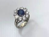 a close up of a diamond and sapphire ring on a white surface