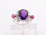 a close up of a ring with a purple stone surrounded by pink and white stones
