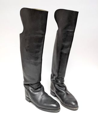 une paire de bottes en cuir noir posées sur une surface blanche, sur fond blanc