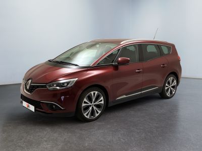 Une voiture rouge est garée dans une pièce aux murs blancs.