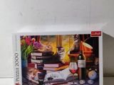 boîte de puzzle représentant un chat et un verre de vin posés sur une table